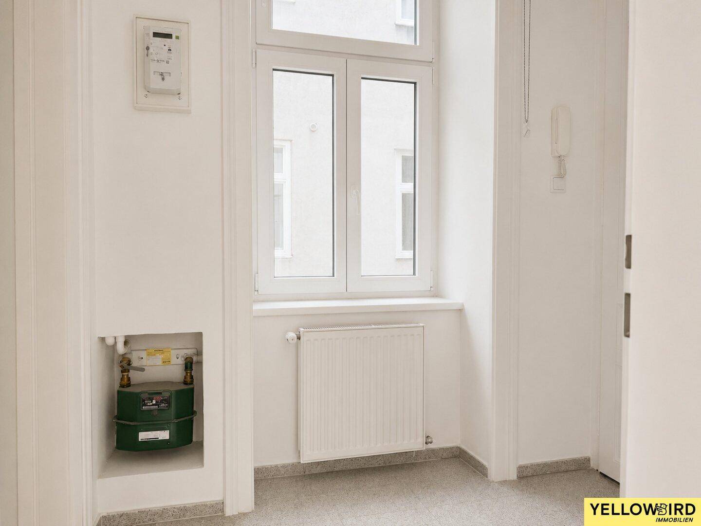 Heller Flur mit Fenster, Heizkörper und Gaszählerinstallation.