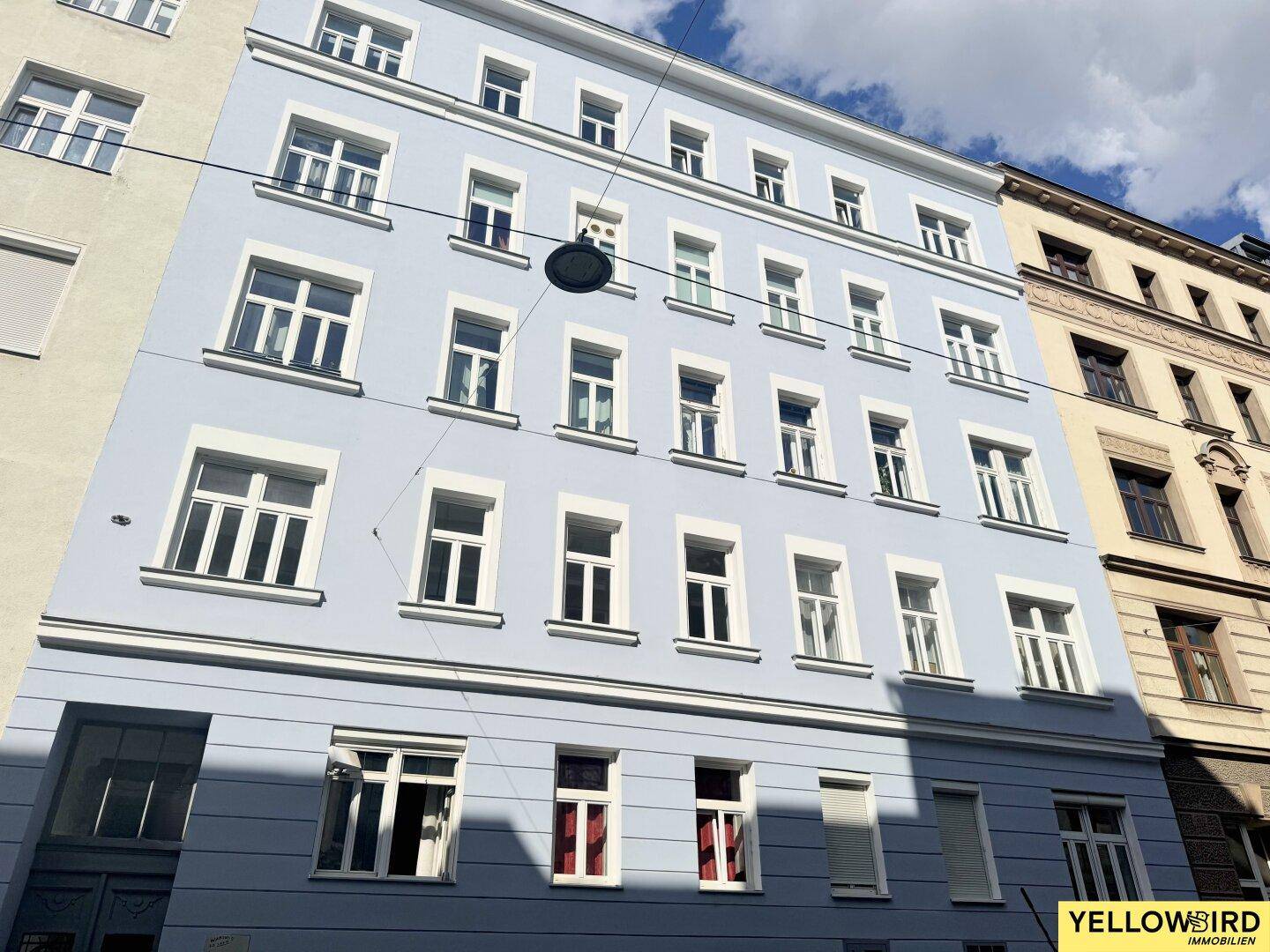 Historisches Gebäude mit blauer Fassade und vielen Fenstern unter blauem Himmel.