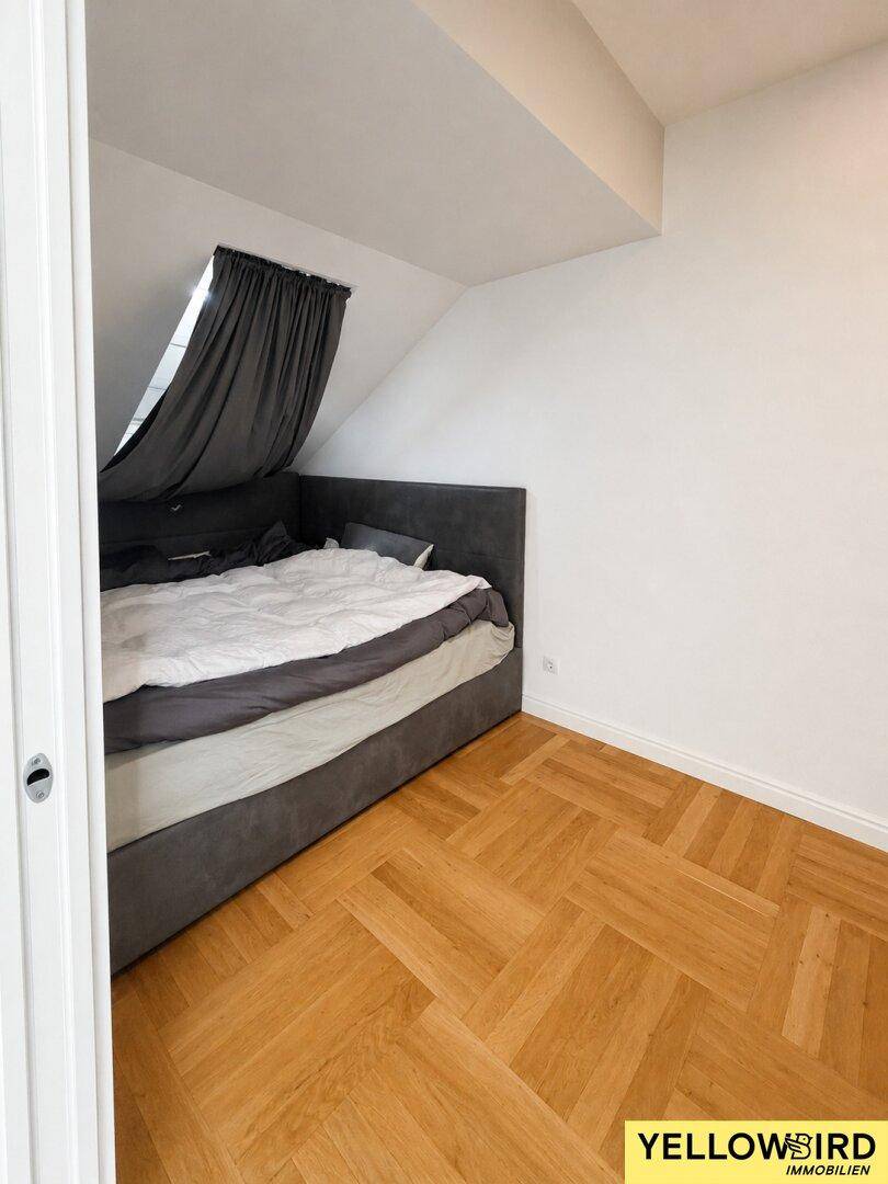 Gemütliches Schlafzimmer im Dachgeschoss mit schrägen Wänden und Parkettboden.