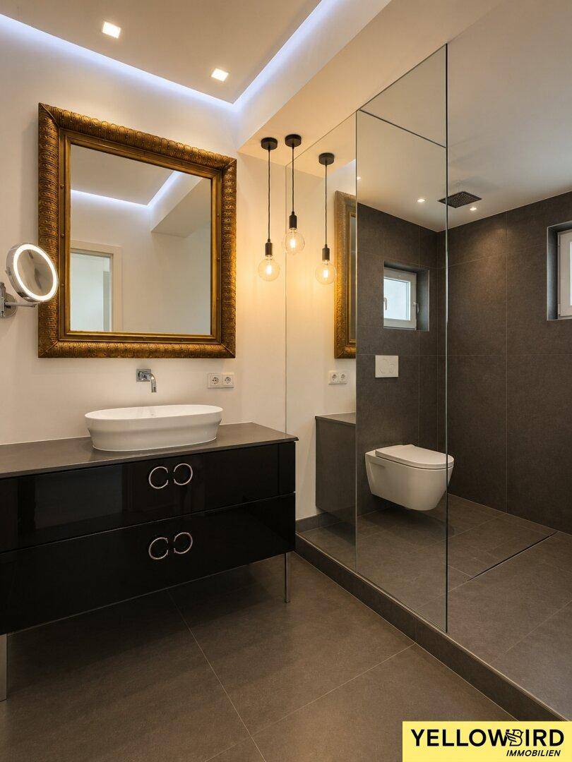 Elegantes Badezimmer mit großem Spiegel, Waschtisch und begehbarer Dusche.