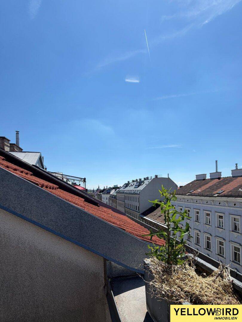Panoramablick über die Dächer der Stadt mit historischer und moderner Architektur unter blauem Himmel.
