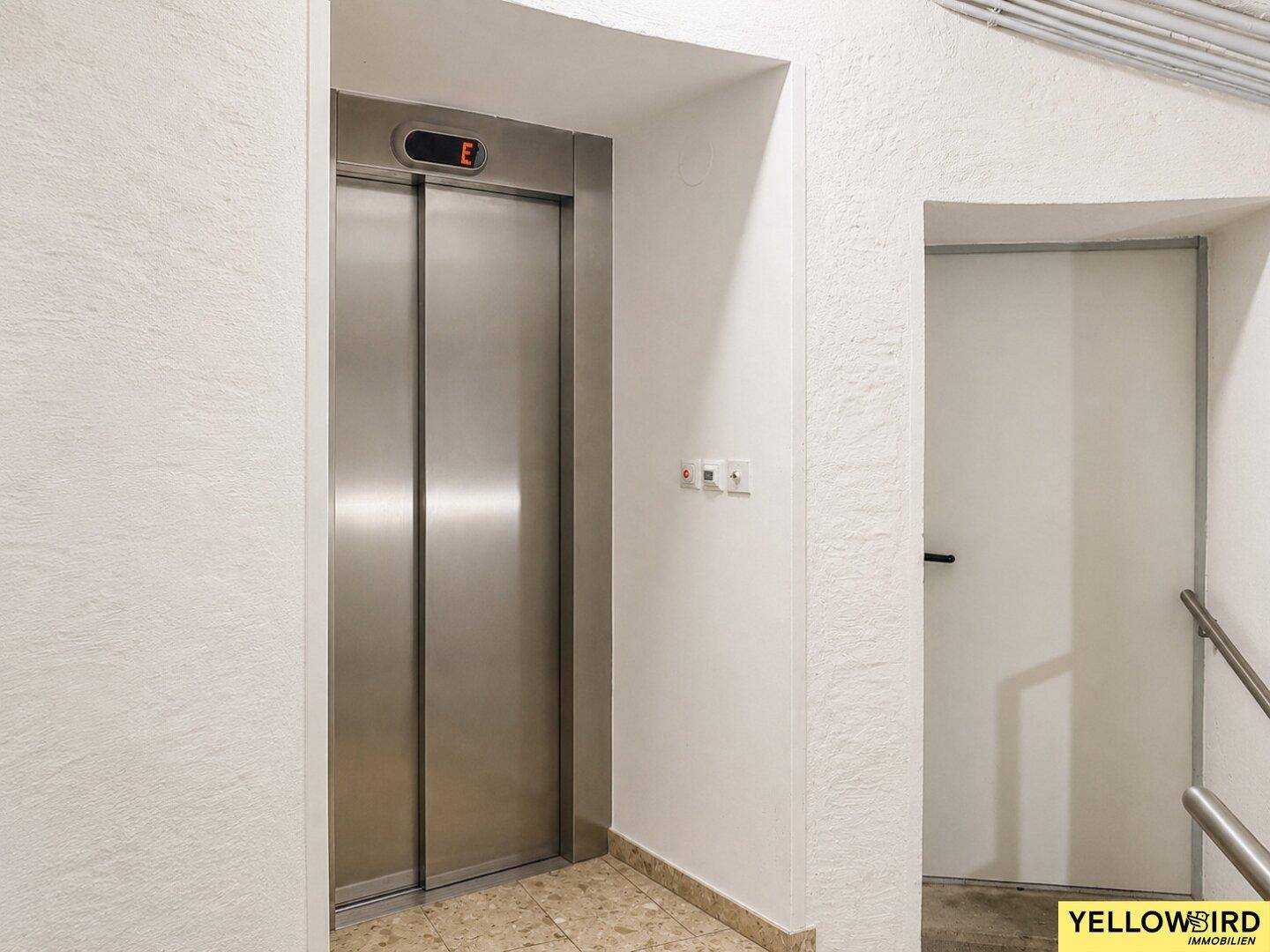Moderner Aufzugsbereich mit Edelstahltüren und hellen Wänden, der Zugang zu den Etagen bietet.
