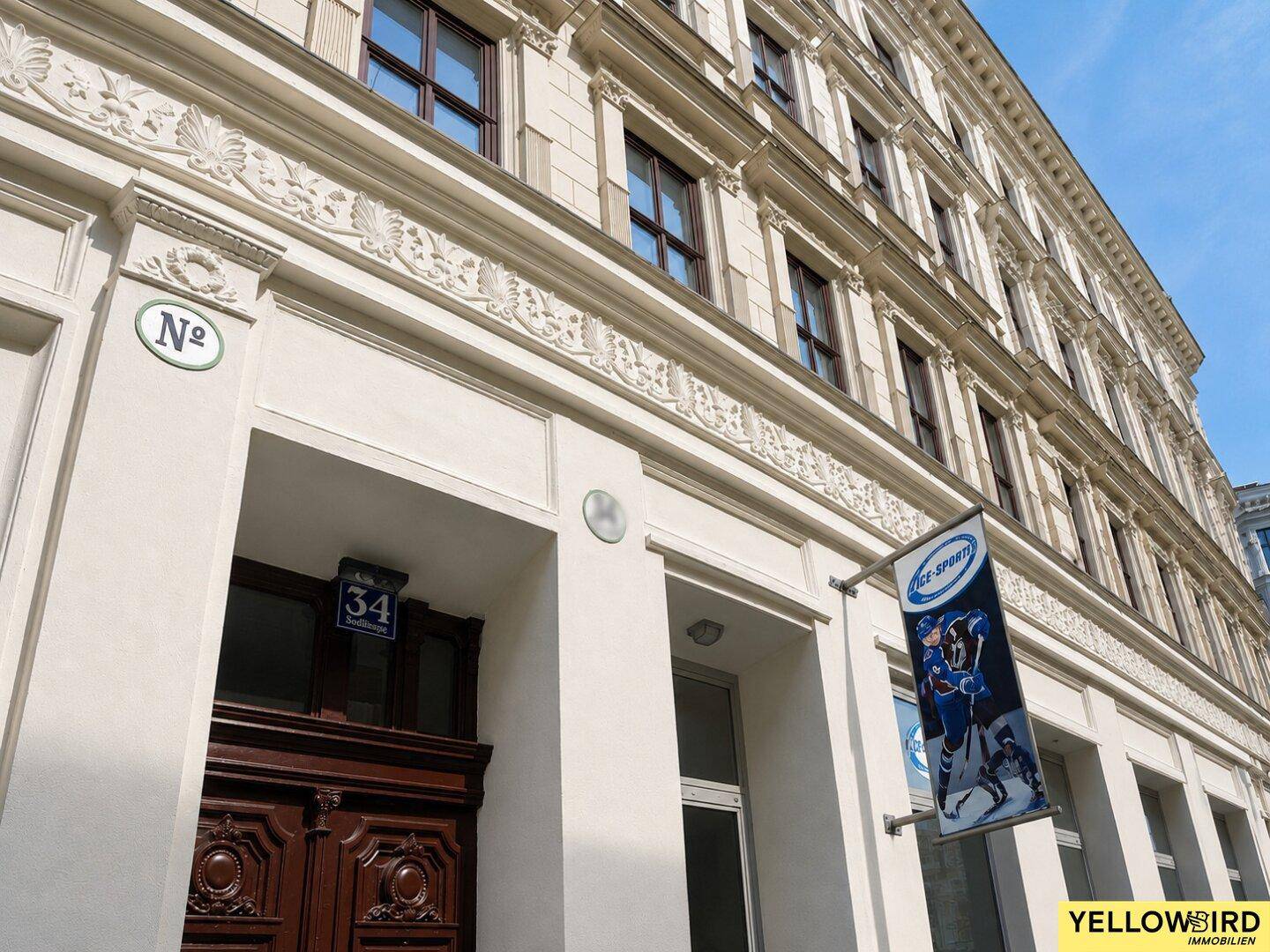 Historische Fassade eines Altbaus mit aufwendigen Stuckverzierungen und großen Fenstern, gut erhalten.
