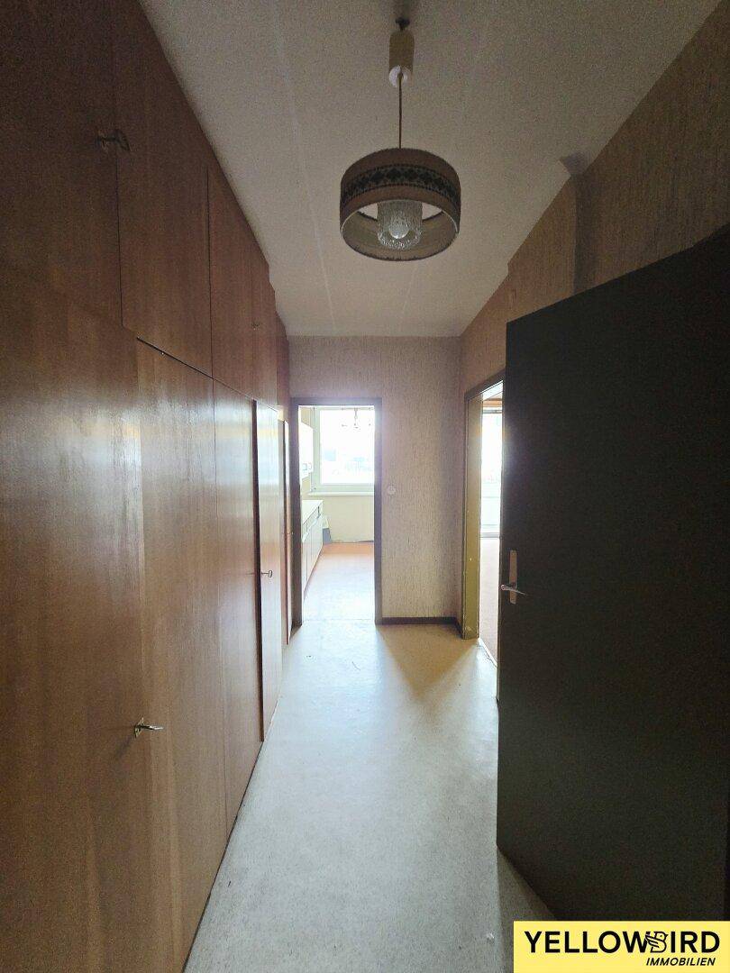 Langer Flur mit Einbauschränken aus Holz und einer Deckenleuchte im Vintage-Stil.