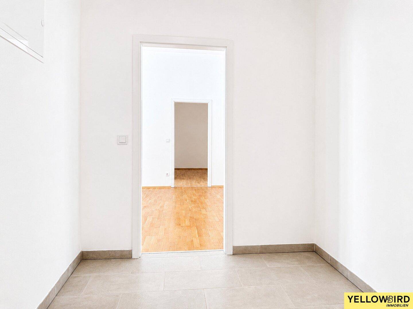 Heller Flur mit Fliesenboden und Durchgang zu einem weiteren Zimmer.
