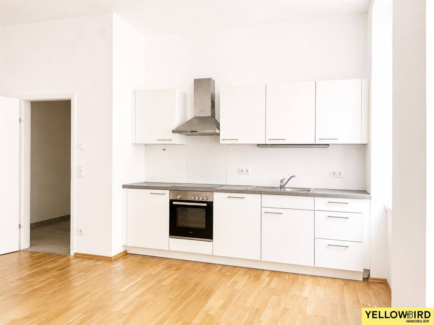 Moderne Einbauküche mit weißen Fronten, integriertem Backofen und Dunstabzugshaube.