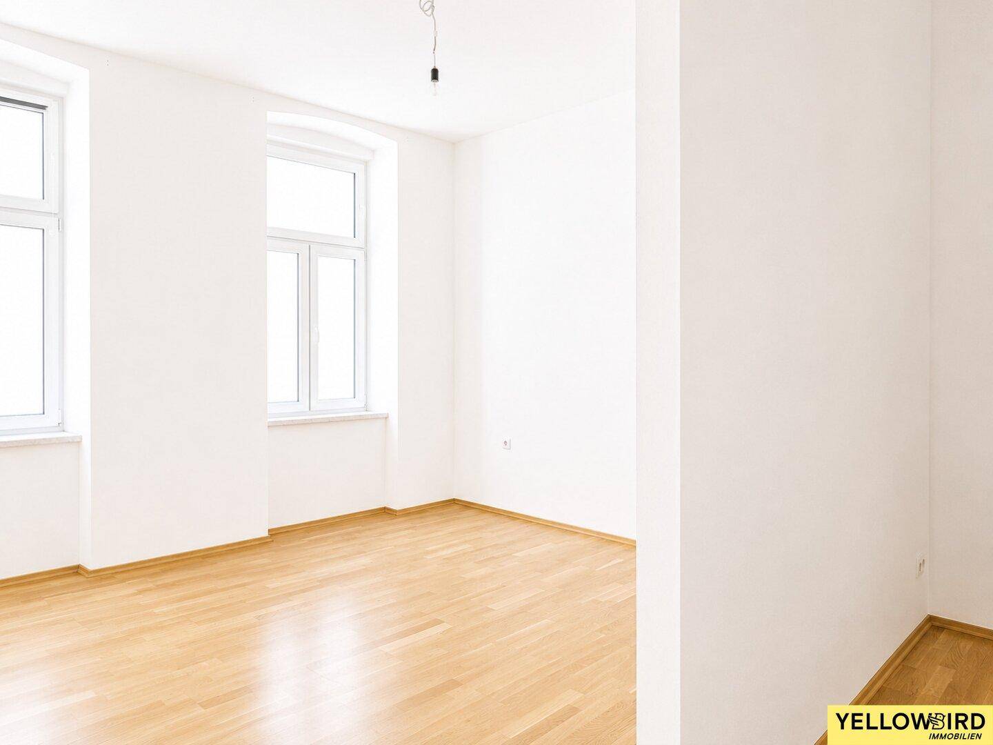 Heller Wohnbereich mit Laminatboden und großen Fenstern, bereit zur Einrichtung.