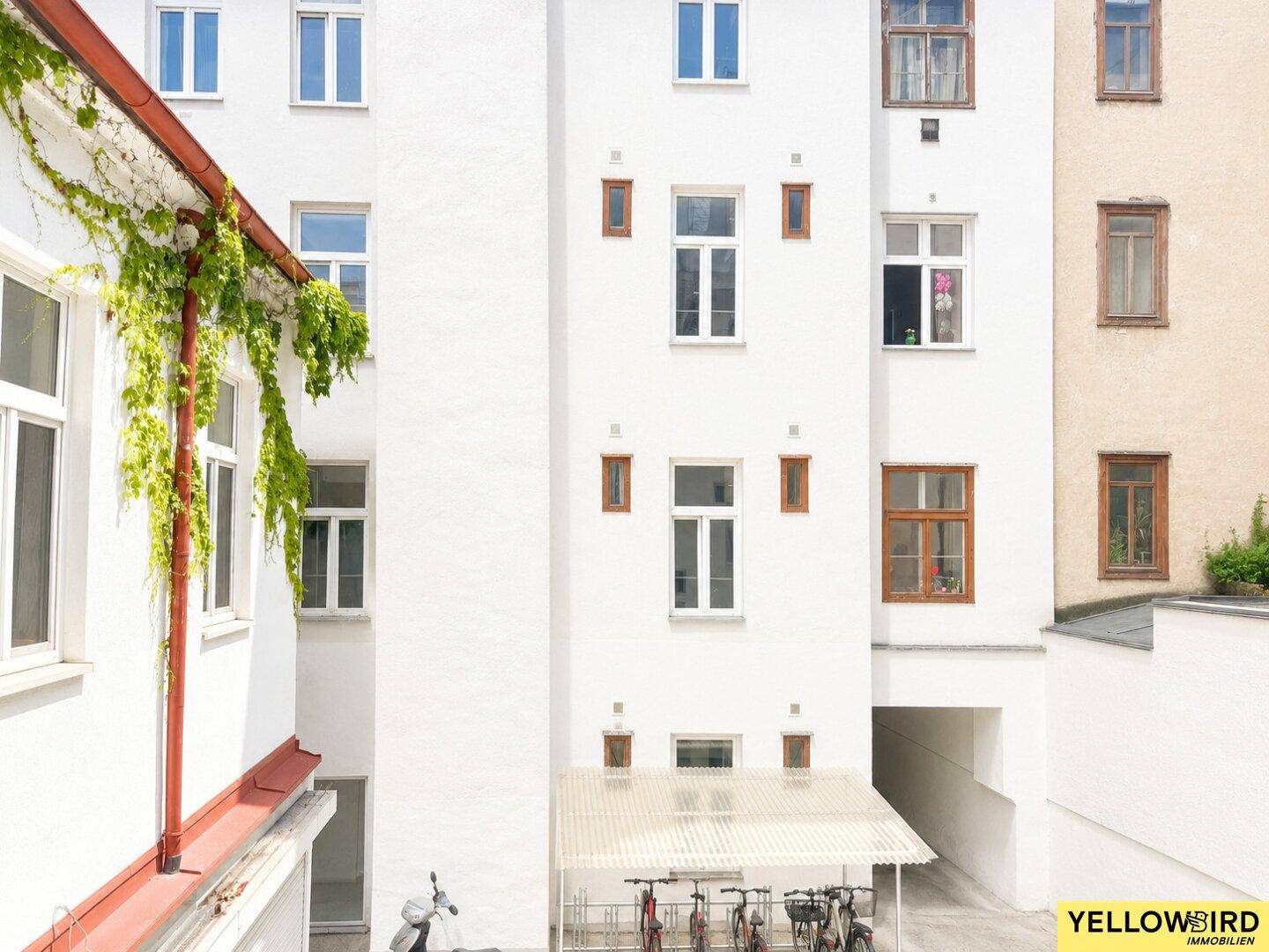 Innenhofansicht eines Wohngebäudes mit Fahrradabstellplatz und begrünten Fassaden.