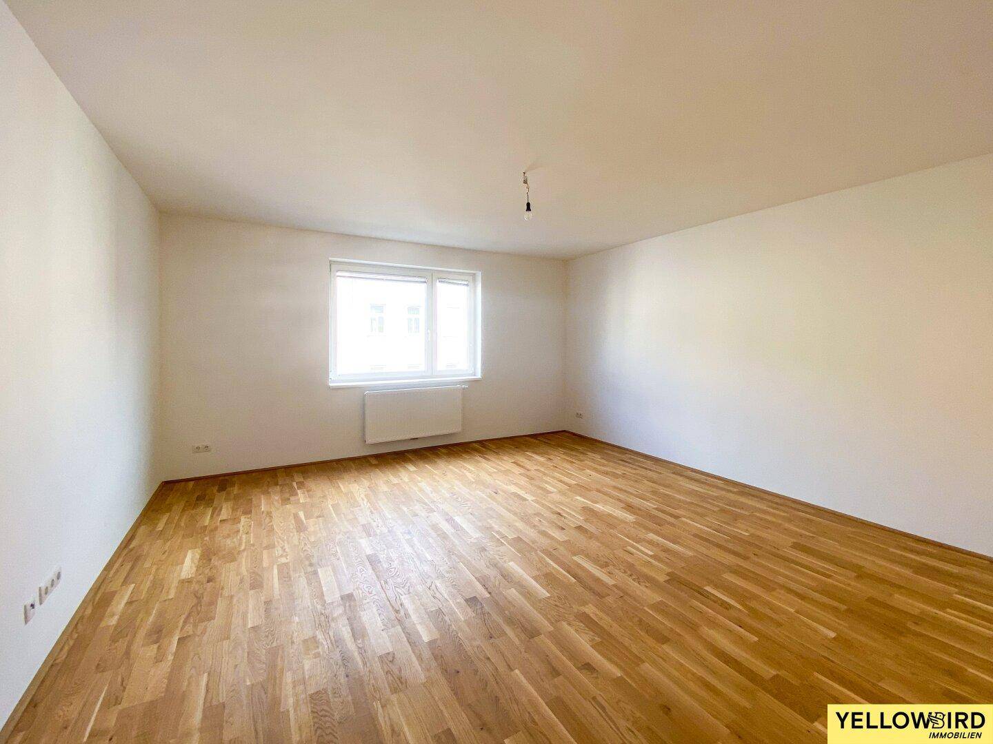 Lichtdurchflutetes Zimmer mit Parkettboden und weiß gestrichenen Wänden, bietet vielseitige Nutzungsmöglichkeiten.
