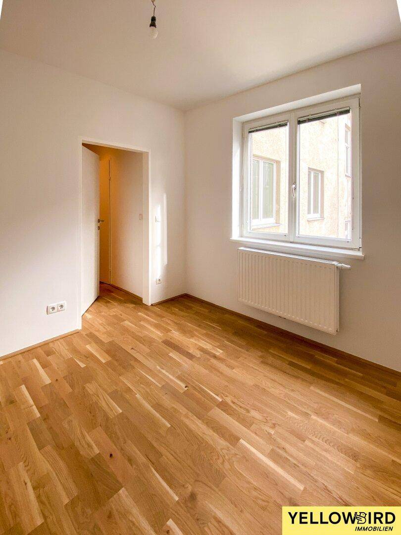 Freundliches Zimmer mit Parkettboden und Heizkörper unter dem Fenster, bereit zum sofortigen Einzug.