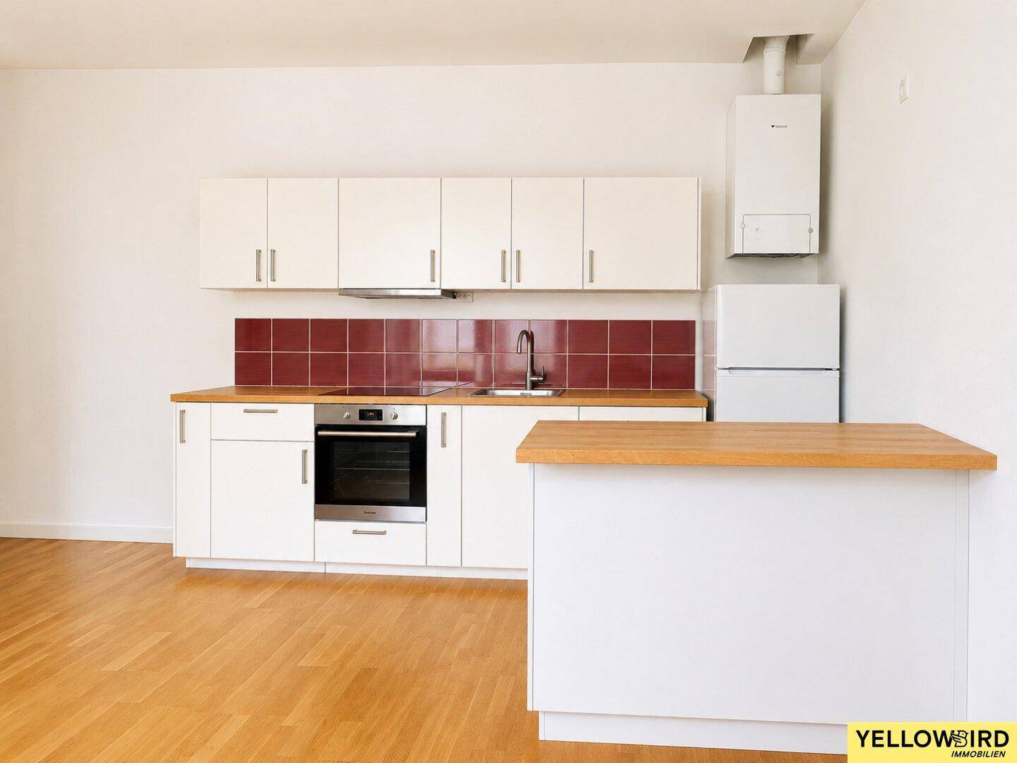 Moderne Einbauküche mit weißen Fronten, Holztheke und roten Fliesen, inklusive Geräten.