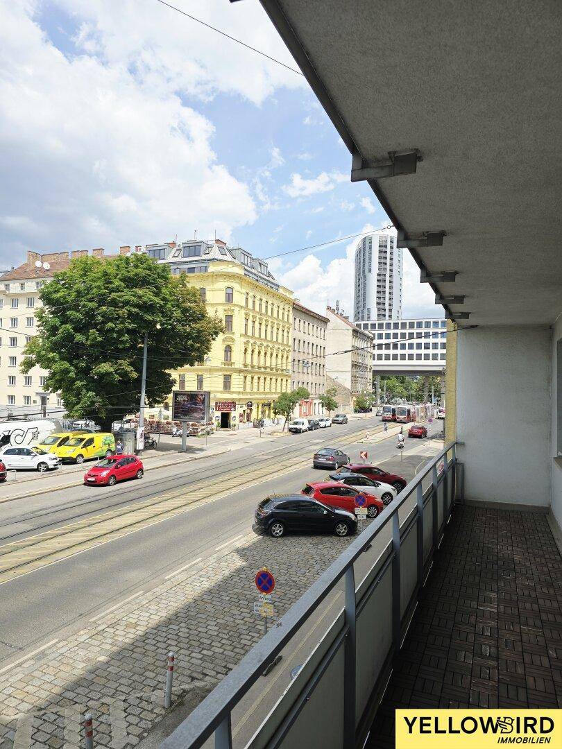Balkon mit Blick auf eine belebte Stadtstraße und die umliegenden Gebäude.