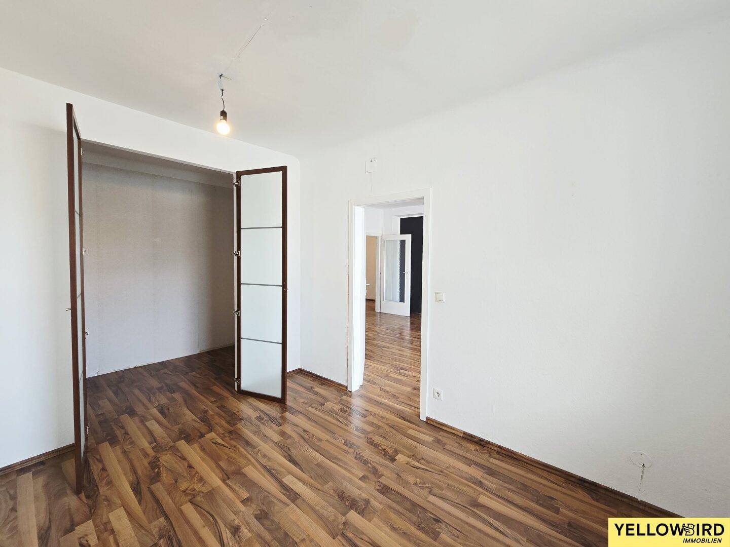 Leeres Zimmer mit Laminatboden und einem offenen Schrankbereich, ideal als Schlaf- oder Gästezimmer.