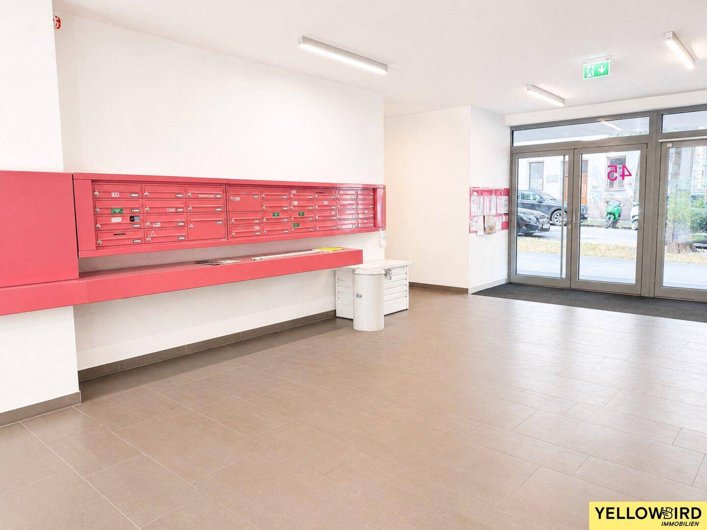 Eingangsbereich des Gebäudes mit Briefkästen und großen Glastüren zum Außenbereich.