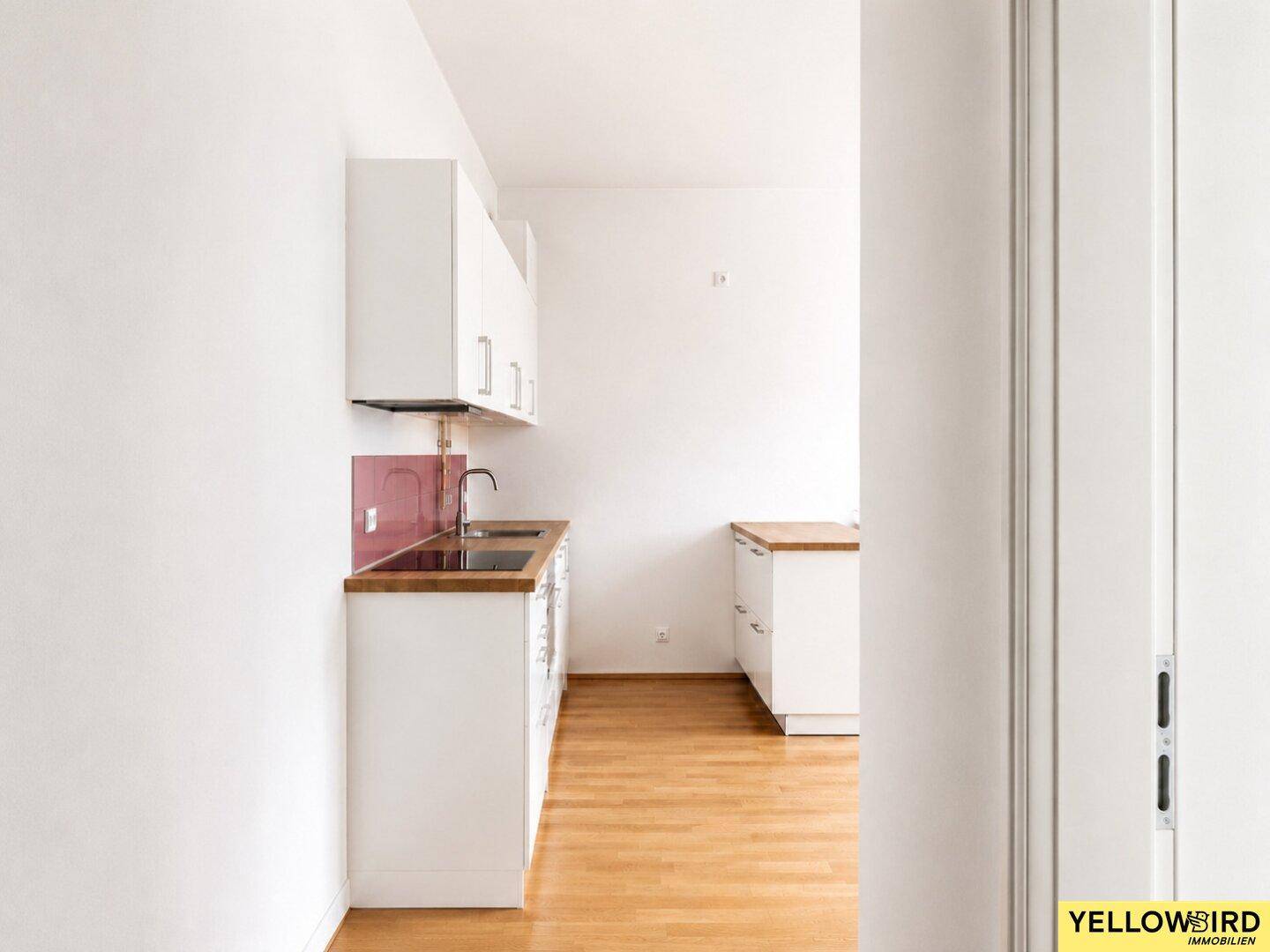 Schmale Küche mit weißen Oberschränken und rotem Fliesenspiegel, ideal für kompakte Räume.