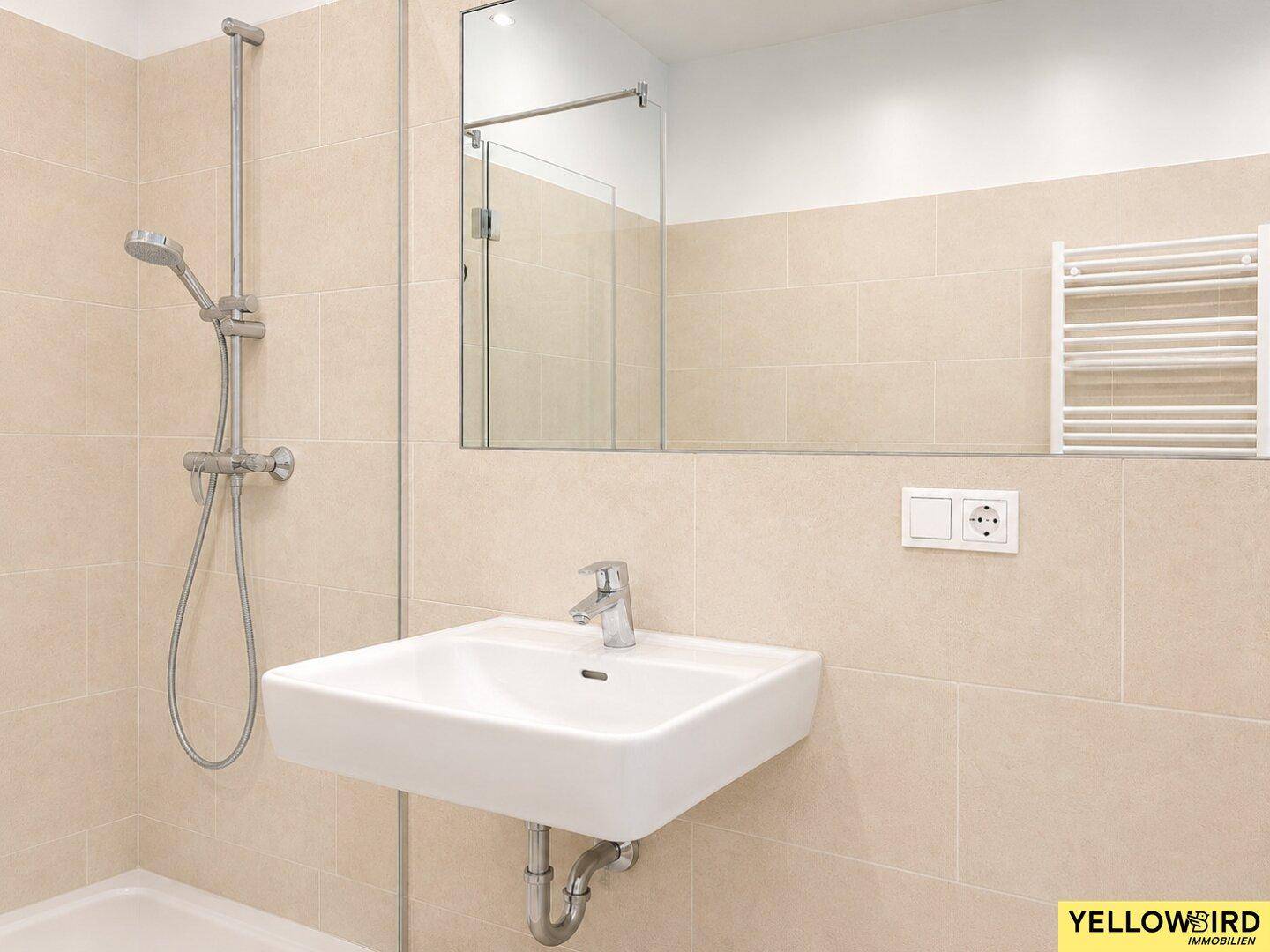 Detailansicht des Waschbeckens und Spiegels in einem modernen Badezimmer mit beigefarbenen Fliesen.