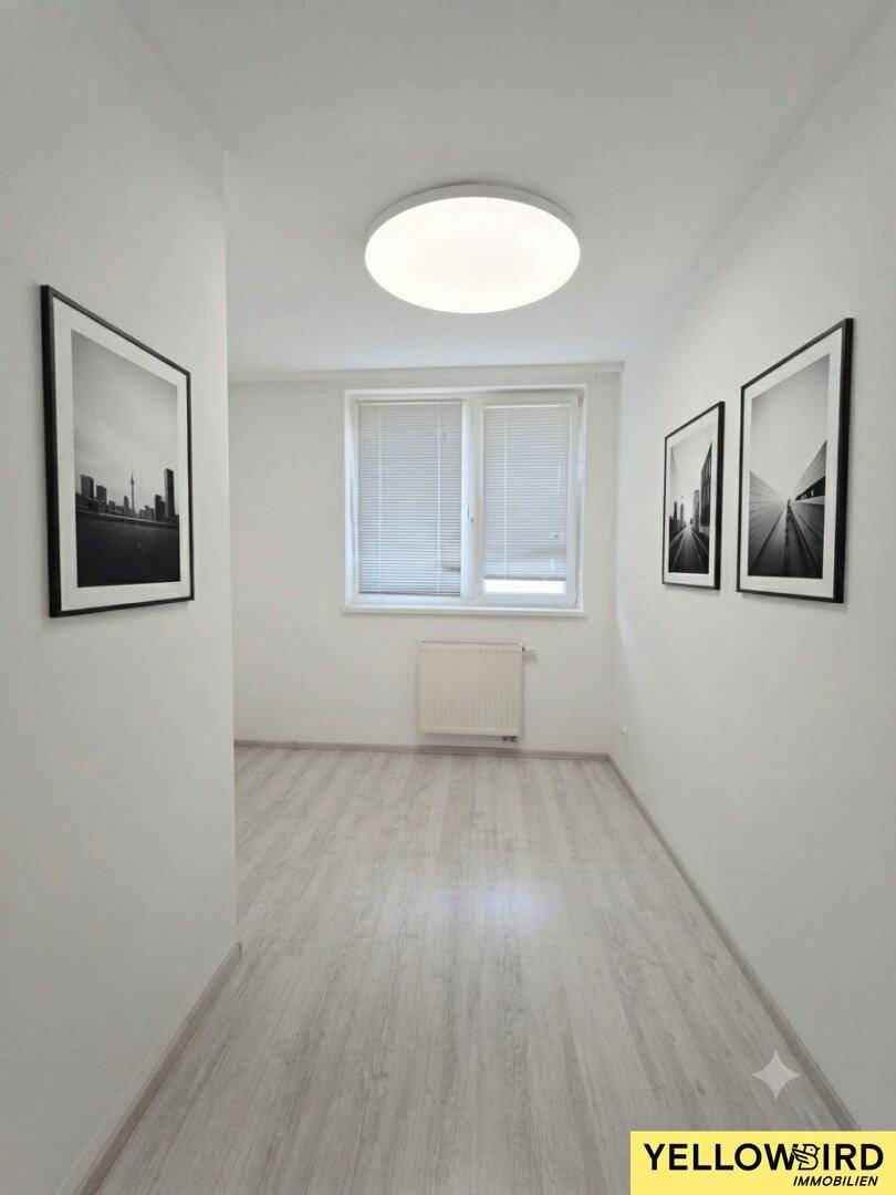 Heller Flur mit modernem Laminatboden, Fenster und schlichten Wanddekorationen.