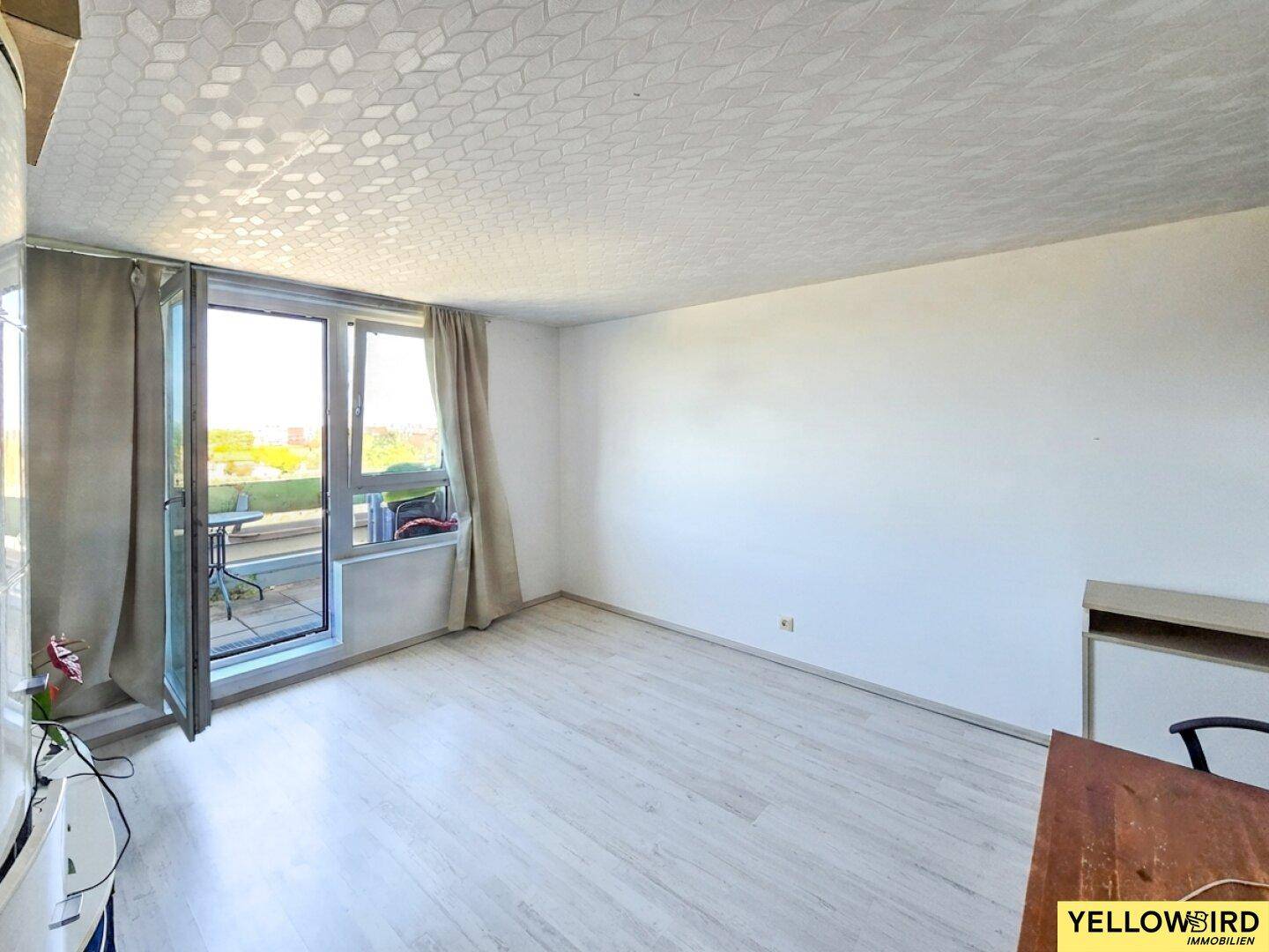Heller, unmöblierter Wohnraum mit hellem Laminatboden und Zugang zu einem Außenbereich.