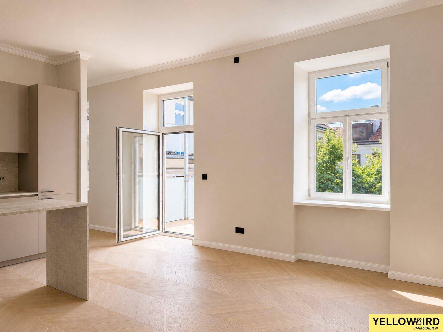 Lichtdurchfluteter Wohnbereich mit Fischgrätparkett, hohen Decken und Zugang zum Balkon.