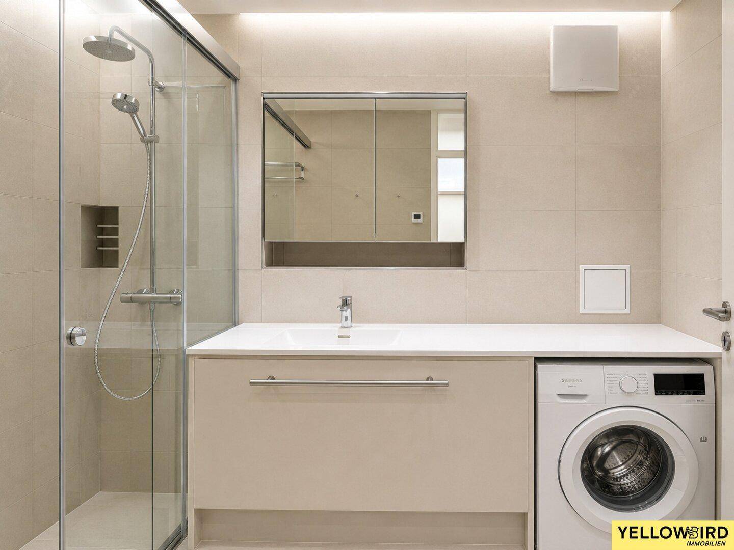 Modernes Badezimmer mit ebenerdiger Dusche, Einzelwaschbecken und integrierter Waschmaschine.
