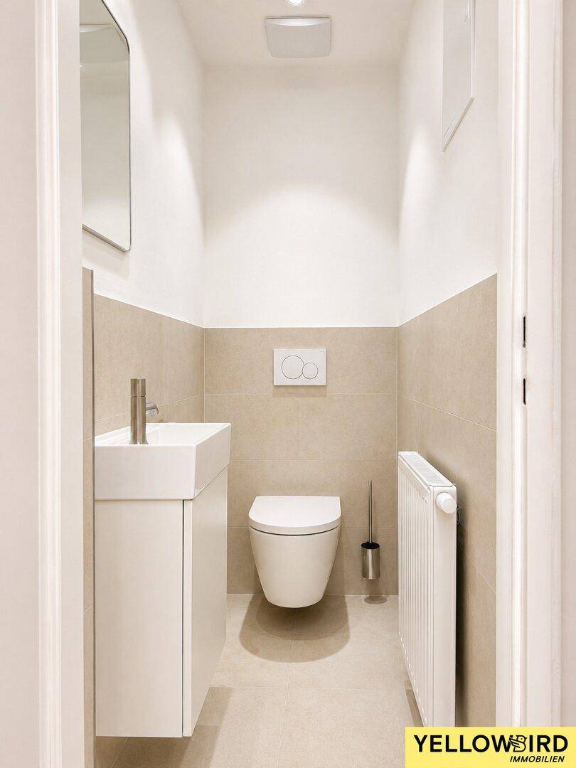 Modernes Gäste-WC mit wandhängender Toilette, kleinem Waschbecken und Heizkörper.