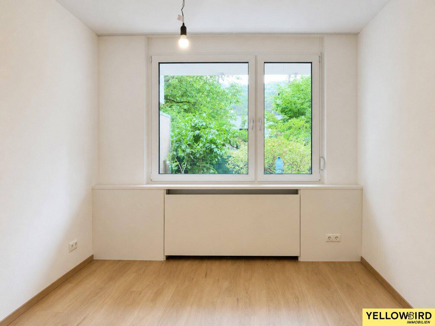 Leerer Raum mit großem Fenster und Blick auf die umliegende grüne Landschaft.