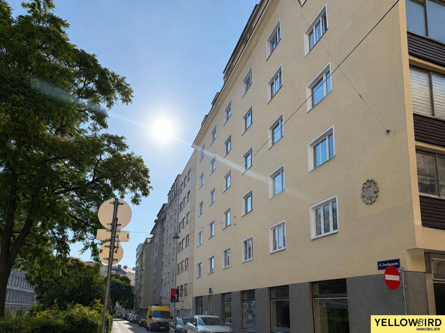 Mehrstöckiges Wohngebäude mit heller Fassade und vielen Fenstern an einem sonnigen Tag.
