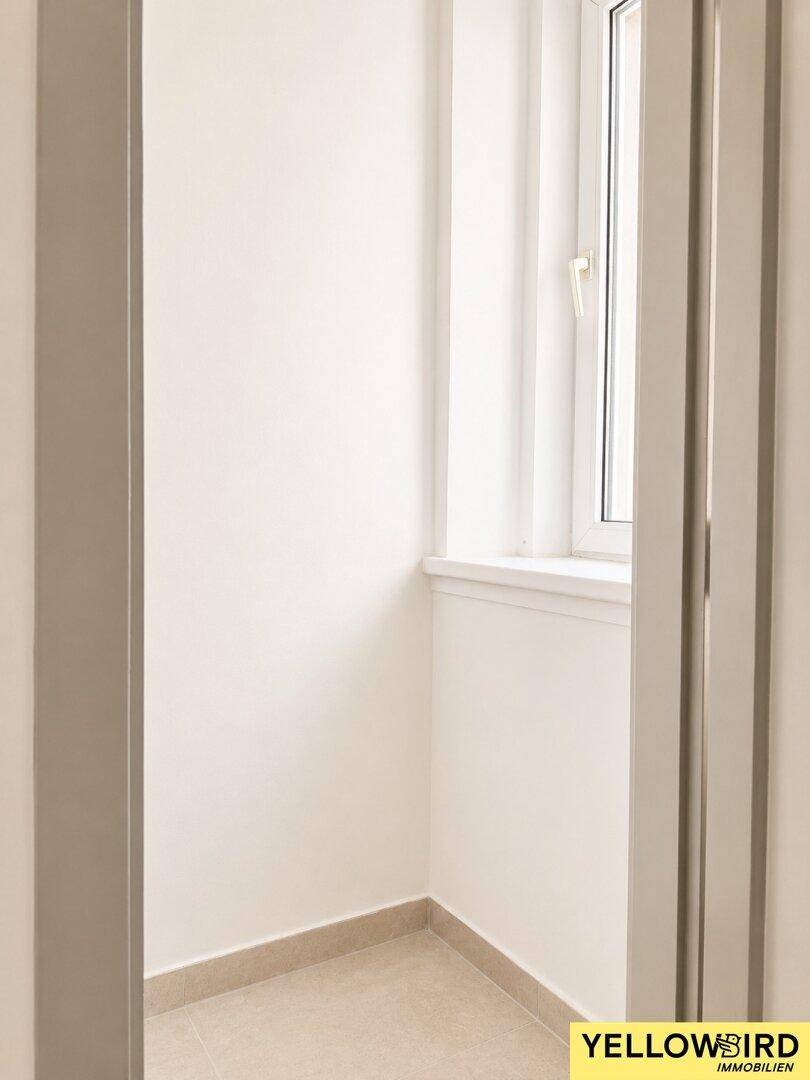 Heller Flurbereich mit Fenster und neutralen Fliesen.