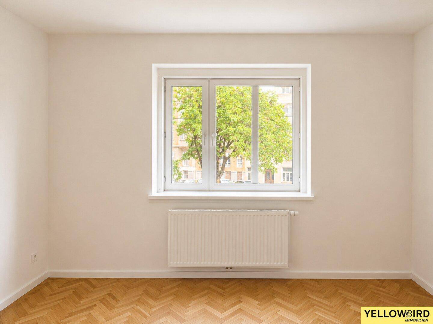 Helles Zimmer mit großem Fenster und Blick auf grüne Bäume.