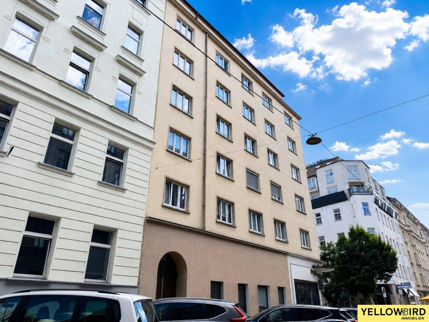 Mehrstöckiges Wohngebäude mit klassischer Fassade und vielen Fenstern in städtischer Umgebung.