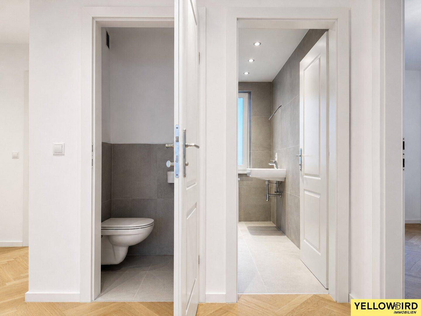 Flur mit Blick auf ein modernes Badezimmer und eine separate Gästetoilette.