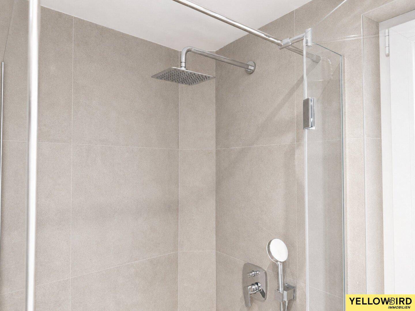 Detailansicht der modernen Regenbrause und Armaturen in der ebenerdigen Dusche.