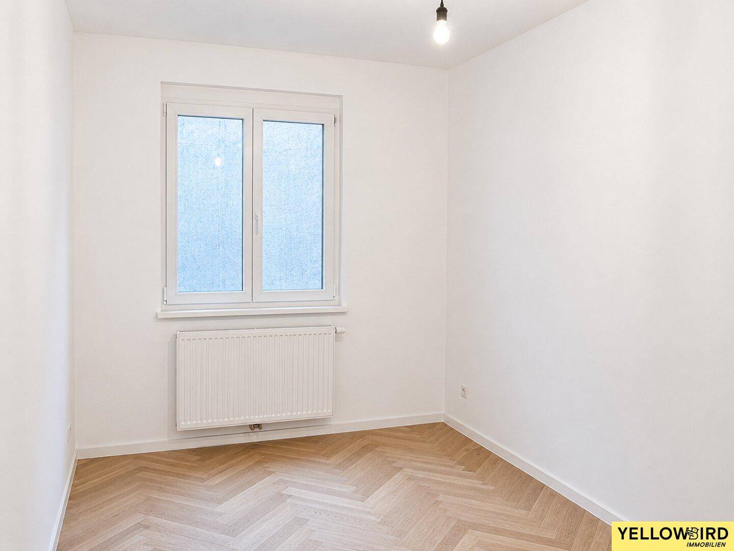 Kleineres Zimmer mit Fischgrätparkett und Fenster, ideal als Kinder- oder Arbeitszimmer.