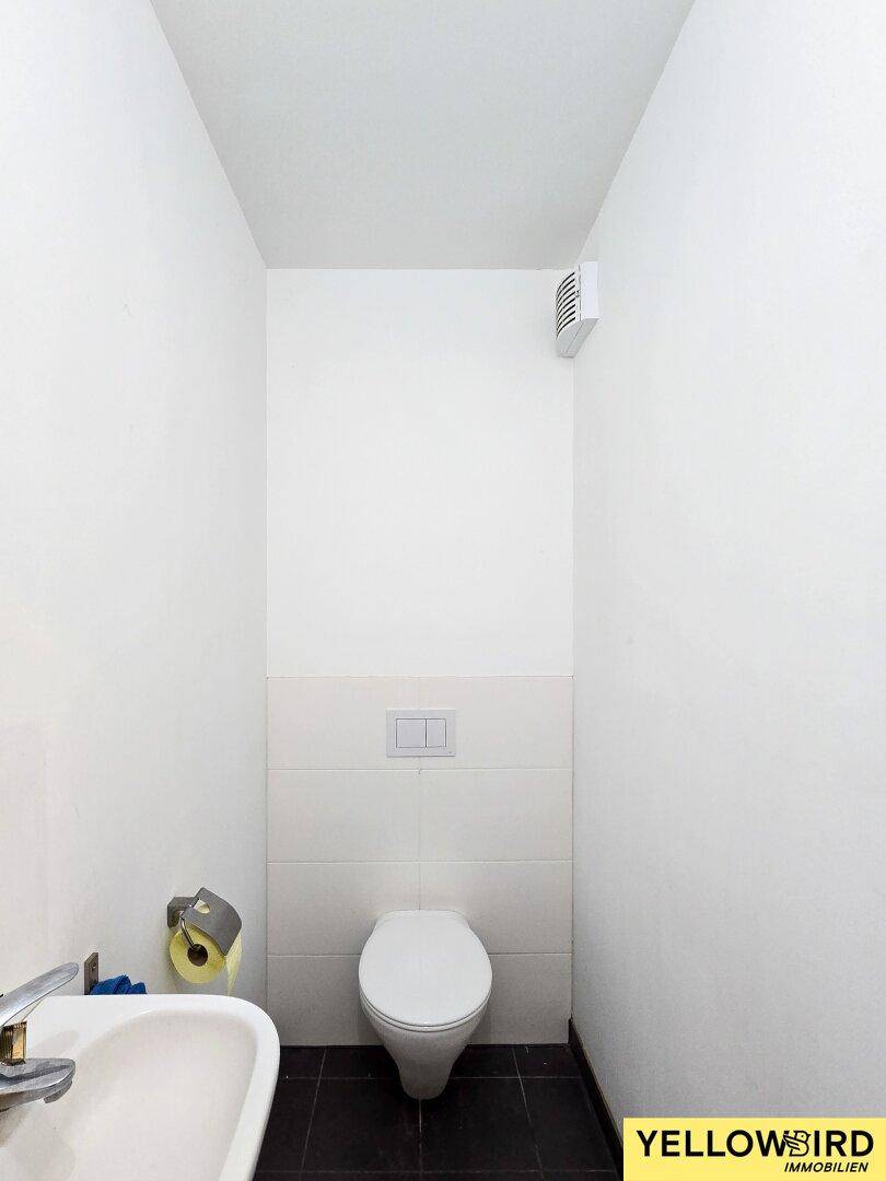 Kleines, helles Gäste-WC mit wandhängender Toilette und dunklen Bodenfliesen.