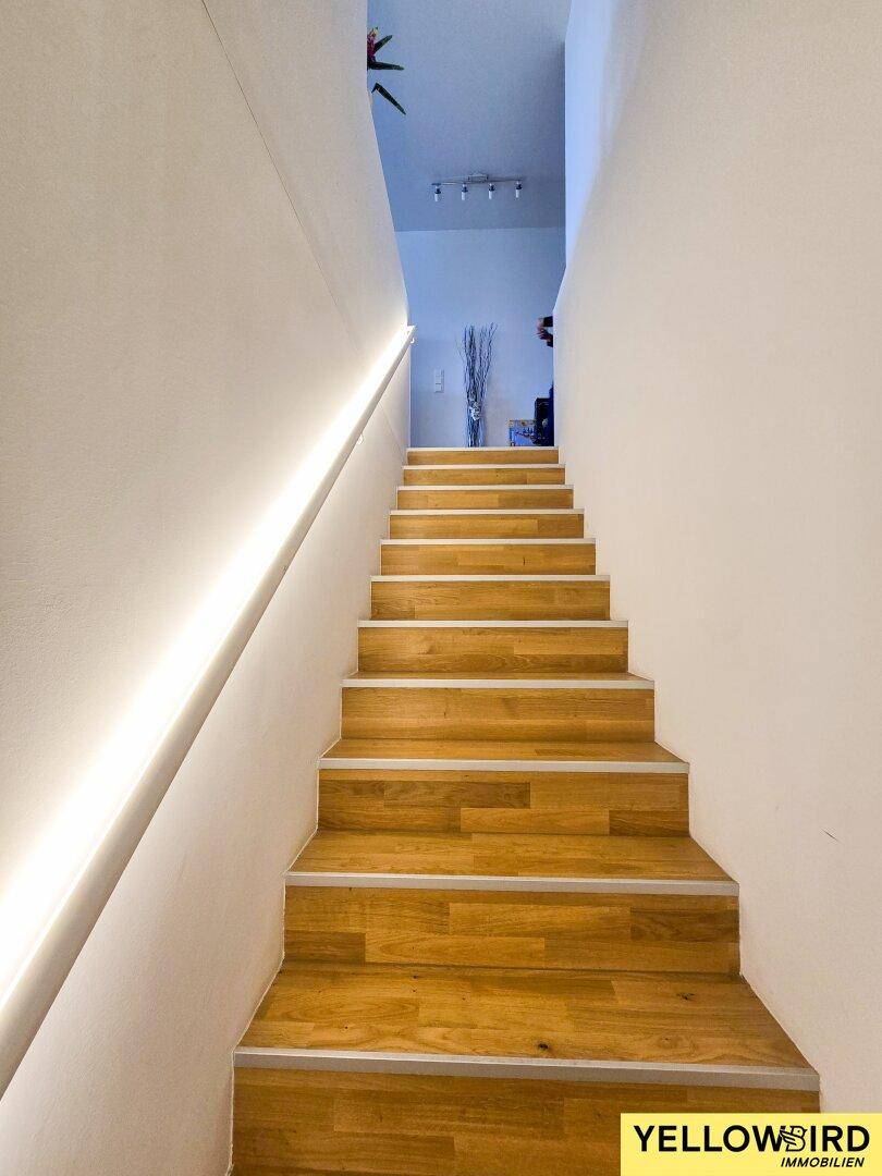 Elegante Holztreppe mit integrierter LED-Beleuchtung, die zu den oberen Etagen führt.