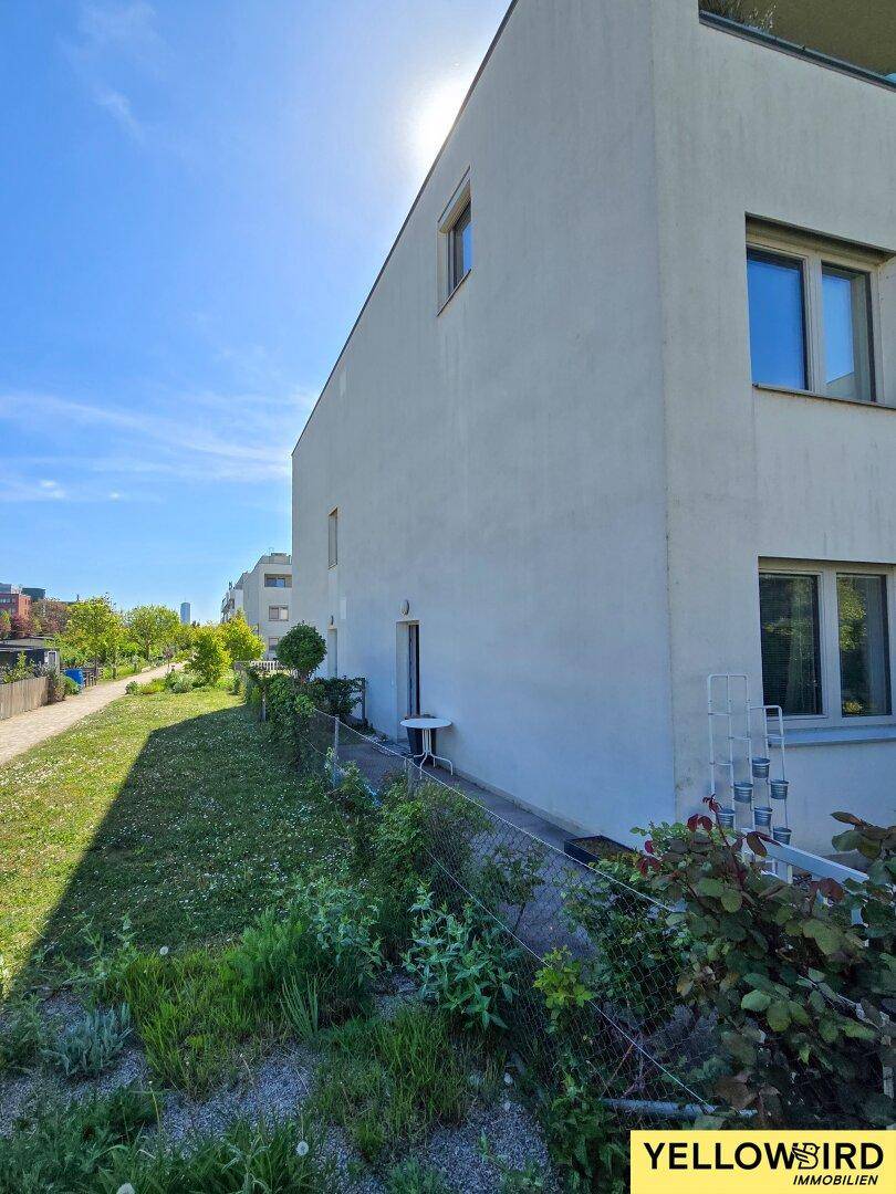 Moderne Gebäudefassade mit schlichtem Design und einer kleinen Grünfläche entlang der Seite.