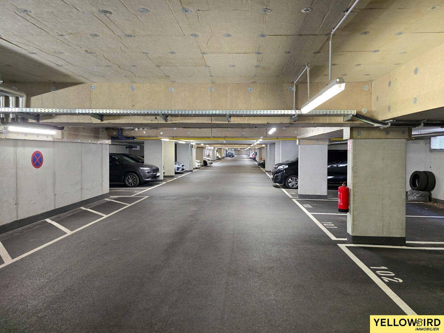 Geräumige Tiefgarage mit zahlreichen Stellplätzen und guter Beleuchtung für Fahrzeuge.