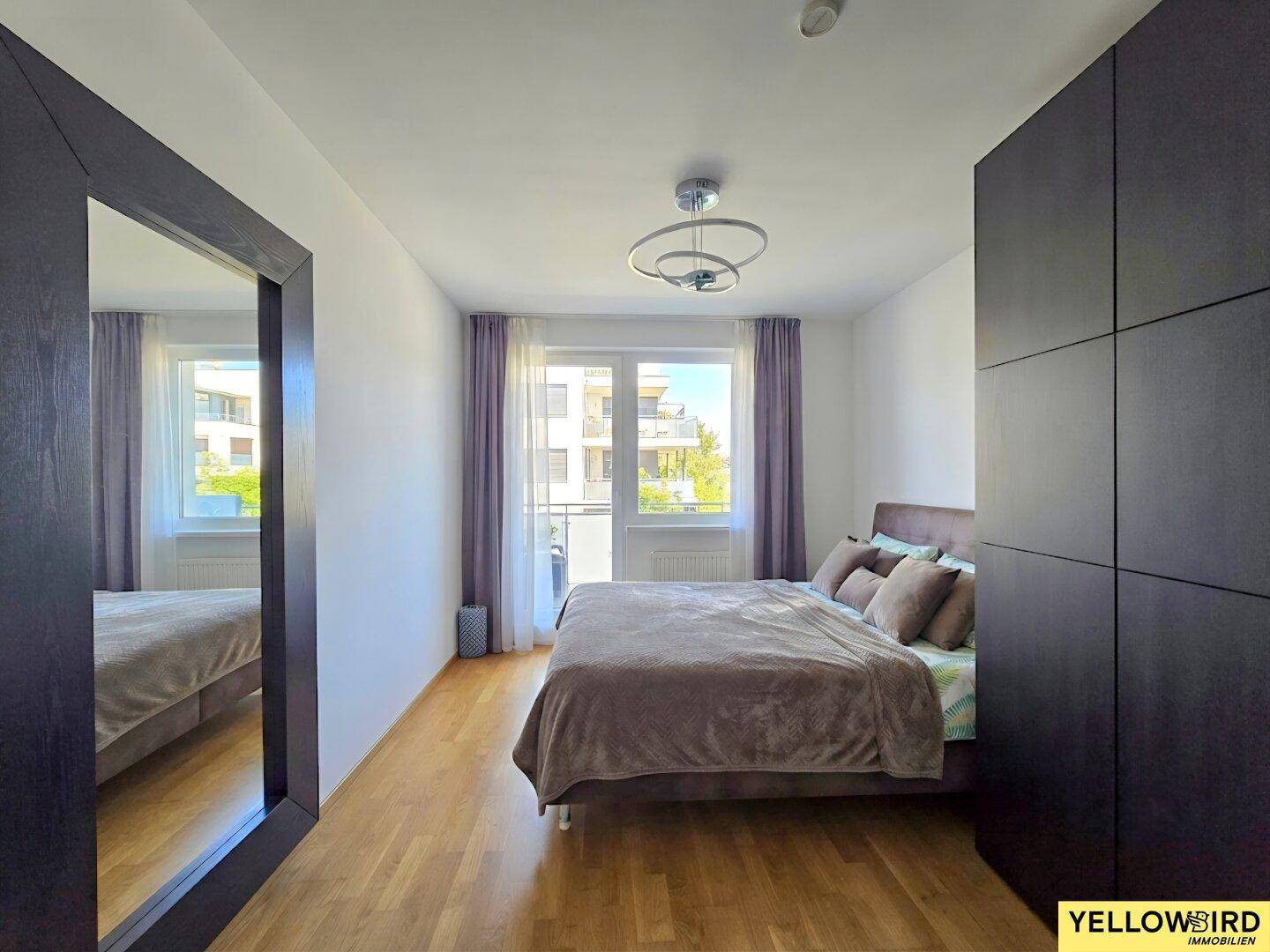 Gemütliches Schlafzimmer mit Doppelbett, dunklen Einbauschränken und großem Spiegel.