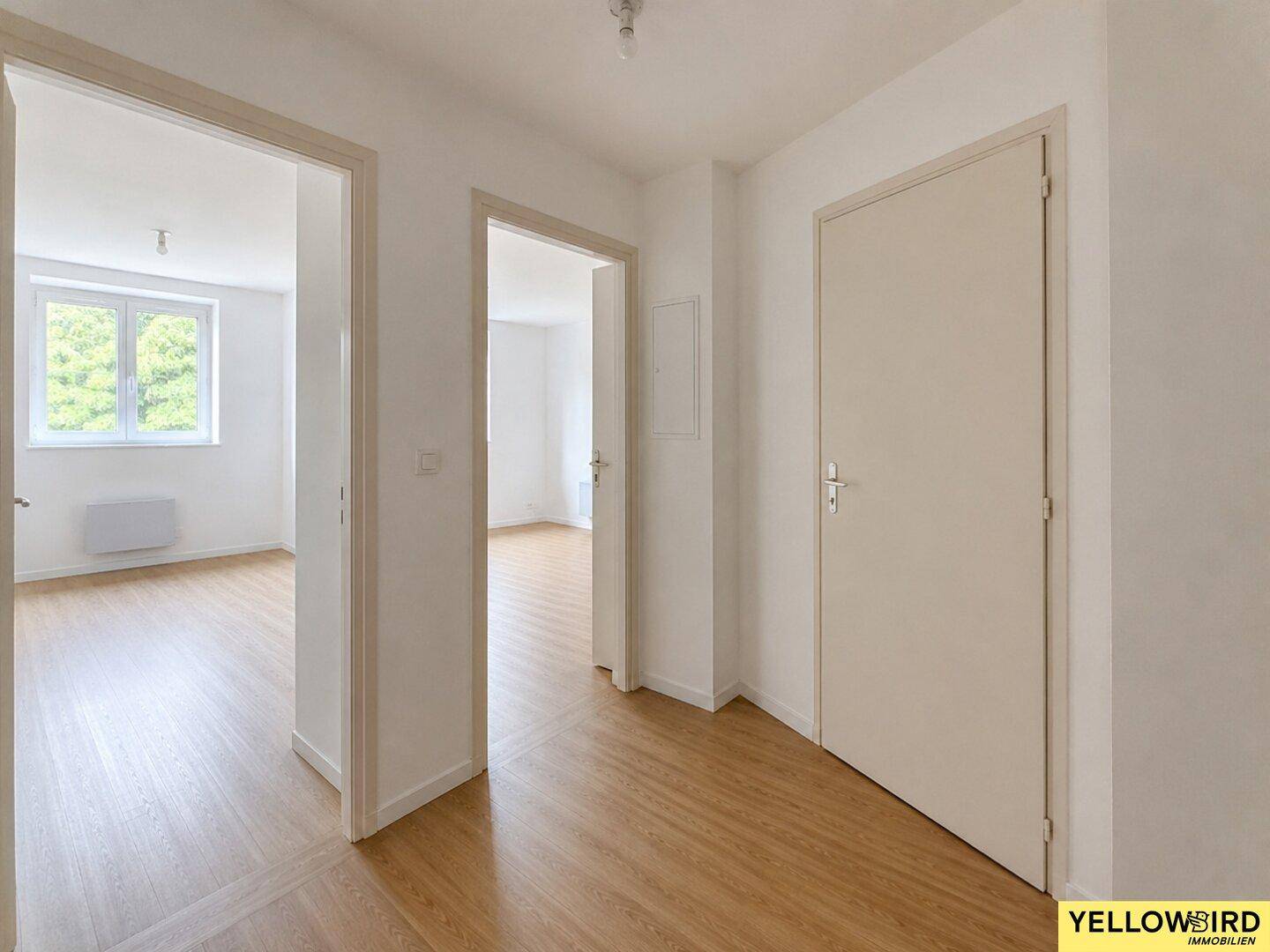 Heller Flur mit Laminatboden und Zugang zu verschiedenen Räumen der Wohnung.
