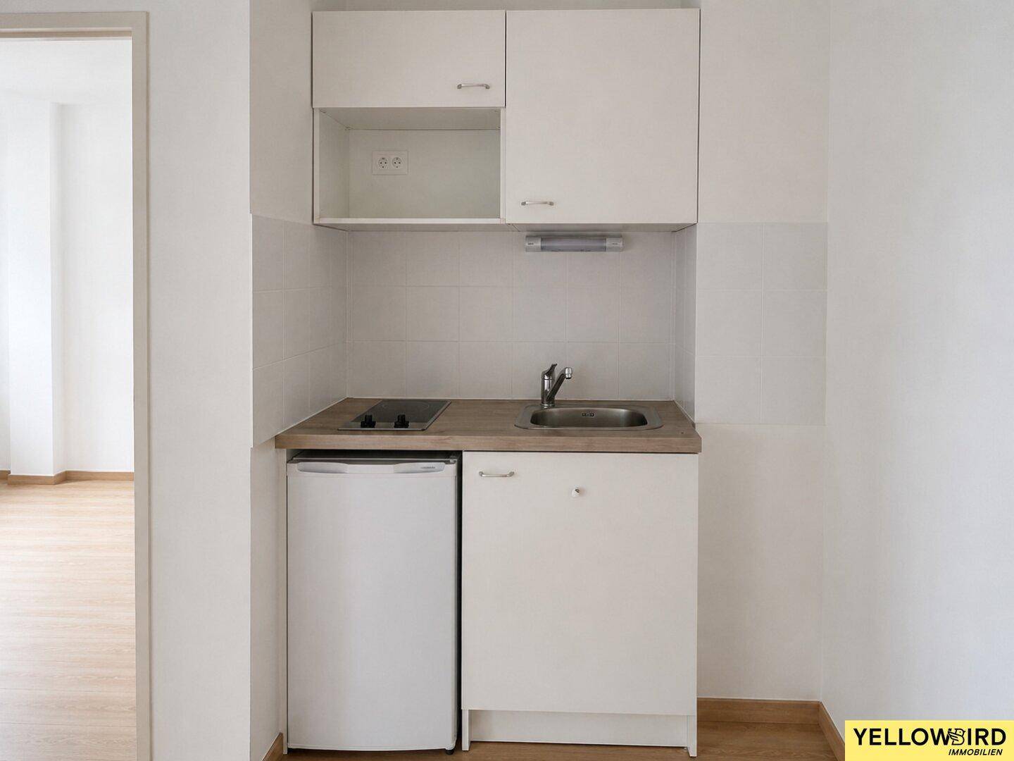 Kompakte Küchenzeile mit Spüle, Kochfeld und Kühlschrank, ideal für kleine Wohnungen.