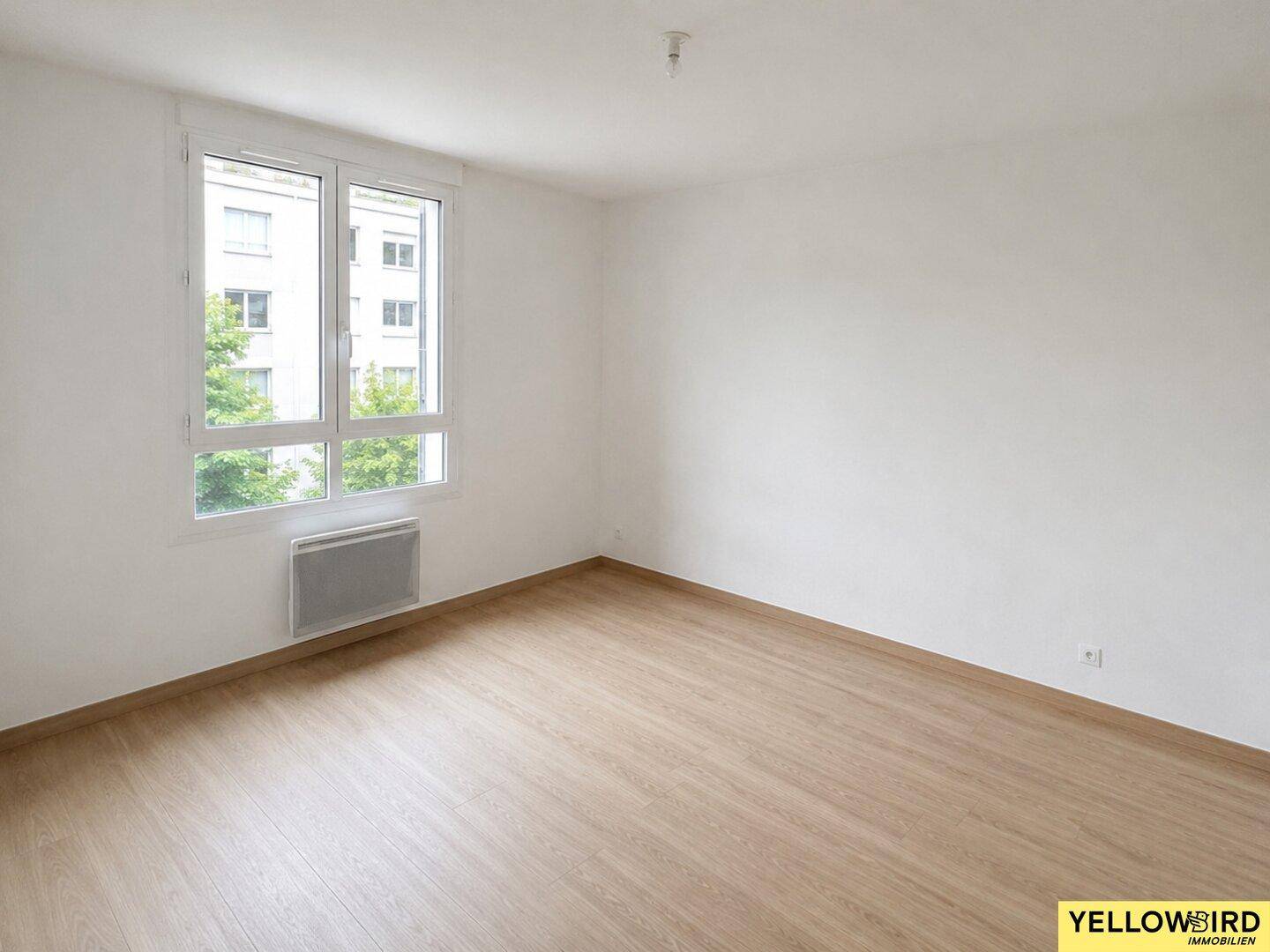 Geräumiges Schlafzimmer mit Laminatboden und großen Fenstern, die viel Tageslicht hereinlassen.
