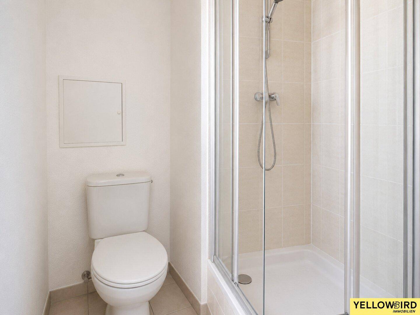 Modernes Badezimmer mit Duschkabine und Toilette, ausgestattet mit hellen Fliesen.
