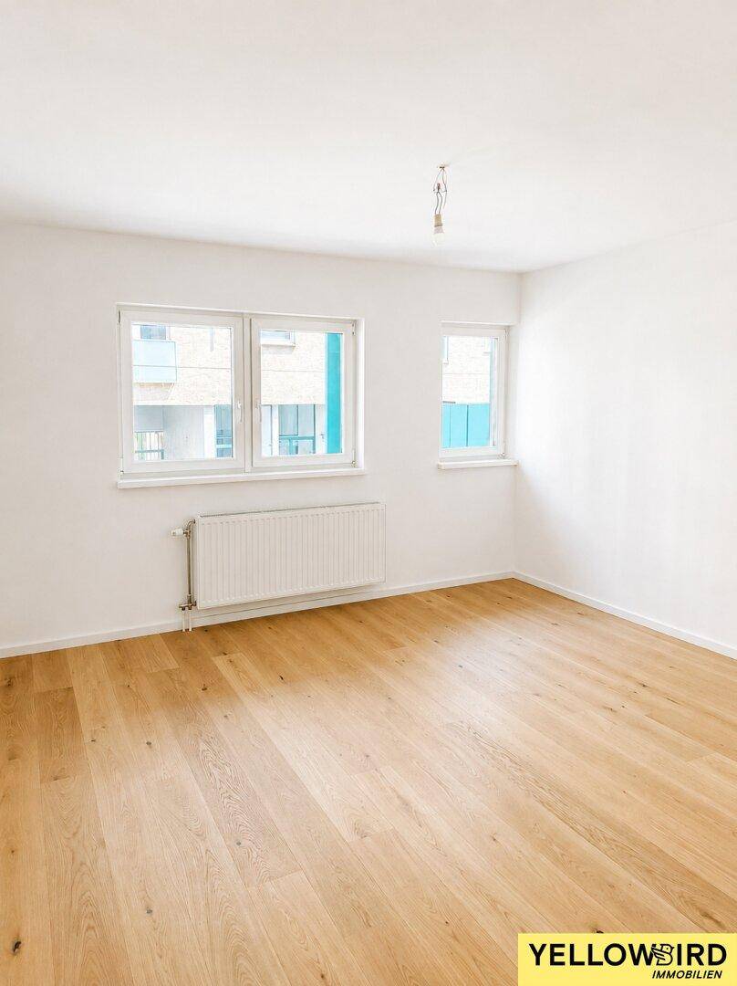 Geräumiger, heller Raum mit zwei Fenstern, Parkettboden und weißen Wänden, bereit zur individuellen Gestaltung.