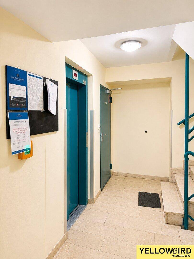 Gemeinschaftsbereich mit einem modernen Aufzug und einer Treppe, die zu den oberen Etagen führt.