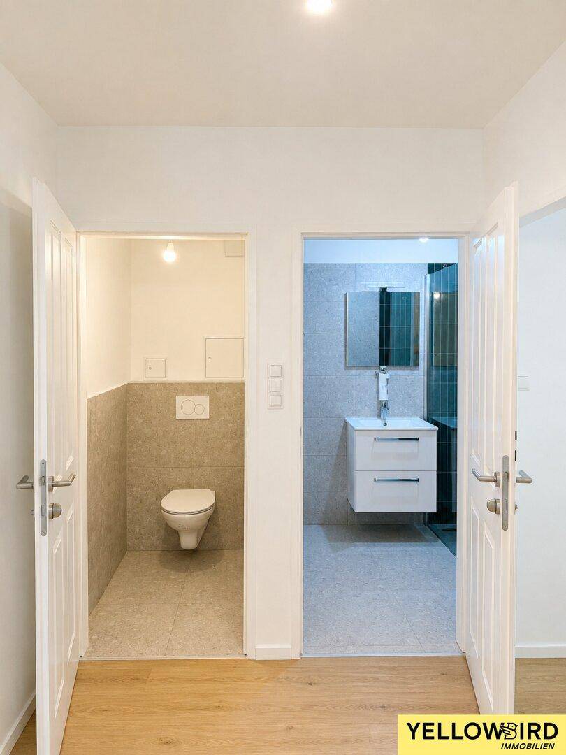 Blick in zwei separate, modern gestaltete Räume: links ein WC, rechts ein Badezimmer mit Dusche.
