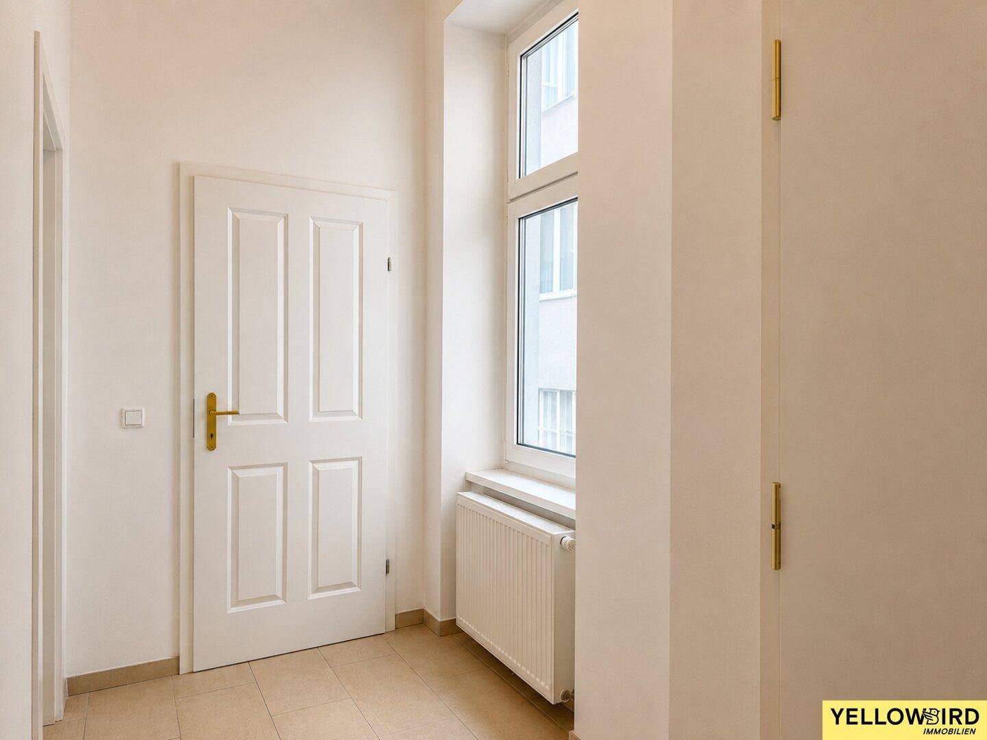 Eingangsbereich mit Fliesenboden, weißer Tür und Fenster, bietet natürlichen Lichteinfall.