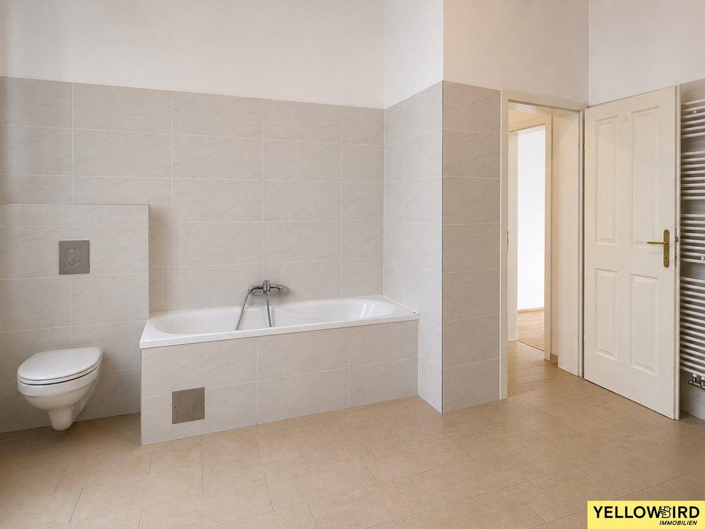 Helles Badezimmer mit Badewanne, Wand-WC und Fliesenboden, in gutem Zustand.