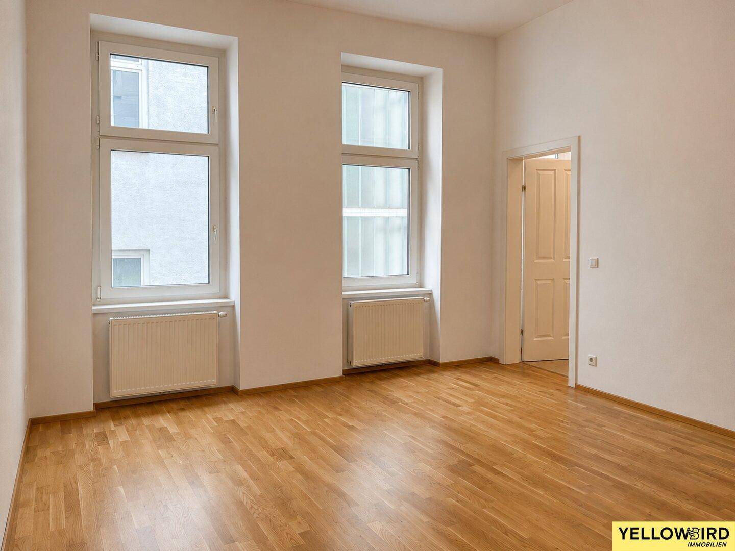 Heller Raum mit Parkettboden und zwei Fenstern, ideal für ein Wohn- oder Schlafzimmer.