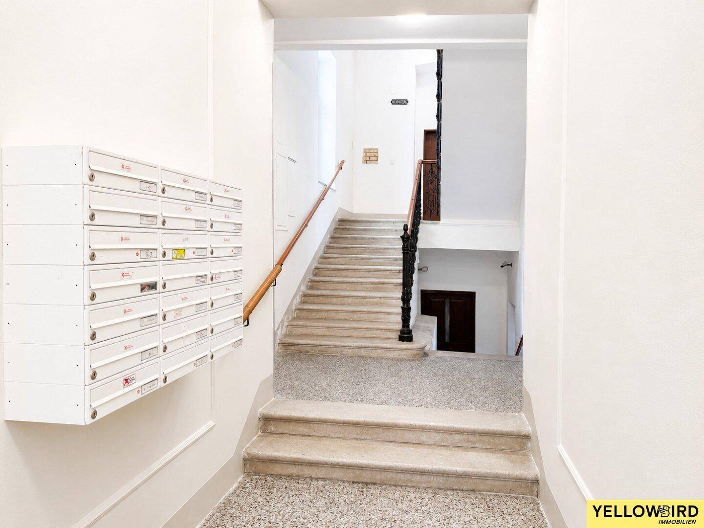 Eingangsbereich des Gebäudes mit Briefkästen und Treppenhaus, in klassischem Stil.