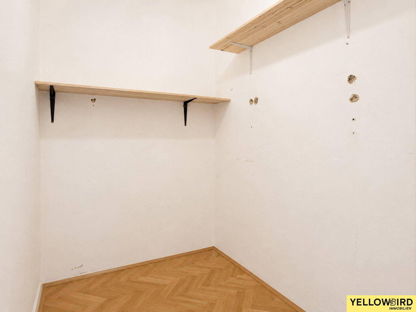 Praktischer Abstellraum mit Holzregalen und Fischgrätparkett, ideal für zusätzlichen Stauraum.